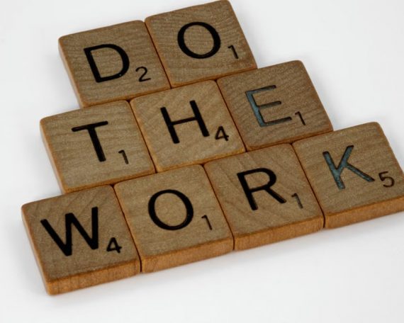 Creative arrangement of Scrabble tiles spelling 'Do the Work' on a white background.