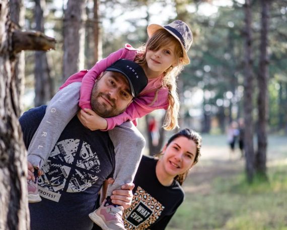 A joyful family enjoying a playful day in a sunlit forest park, capturing the essence of togetherness.